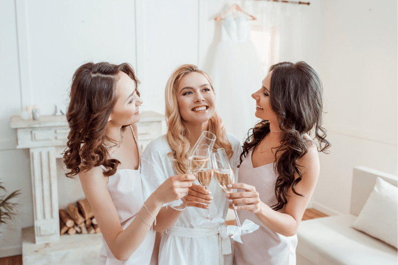 Bride and bridesmaids drinking champagne pre wedding revenue