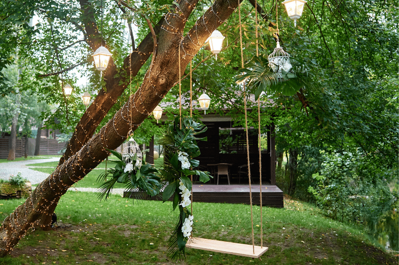 Outdoor tree swing with fairy lights and lanterns wedding venue props