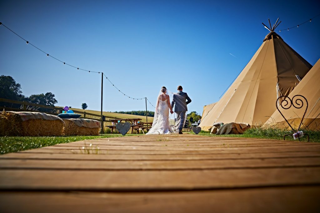 Bridal couple walking by a teepee