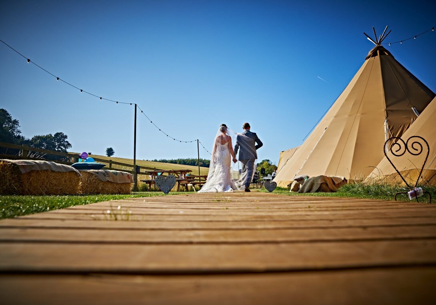 Bridal couple walking by a teepee
